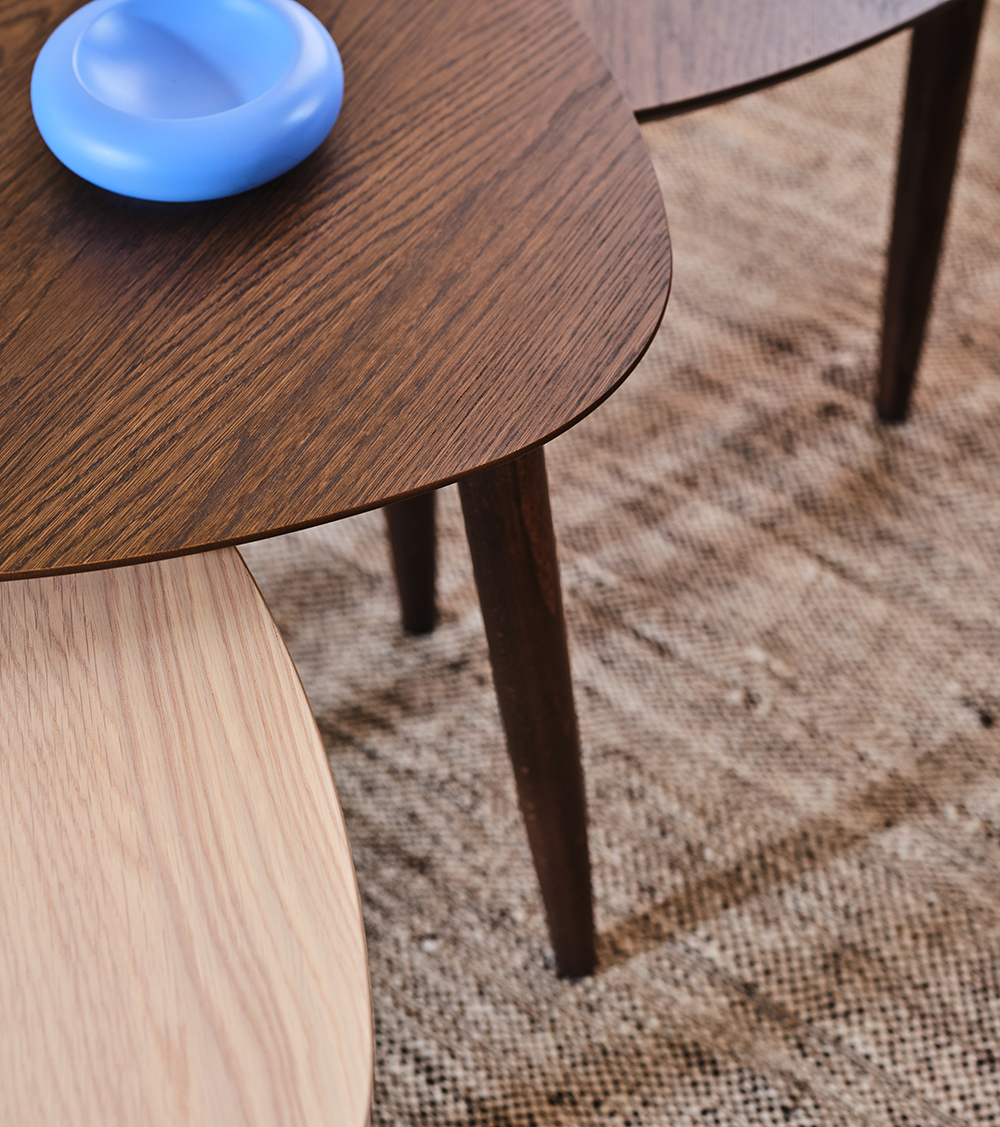 Närbild på två bord. Ett med ljust trä och ett med mörkt.